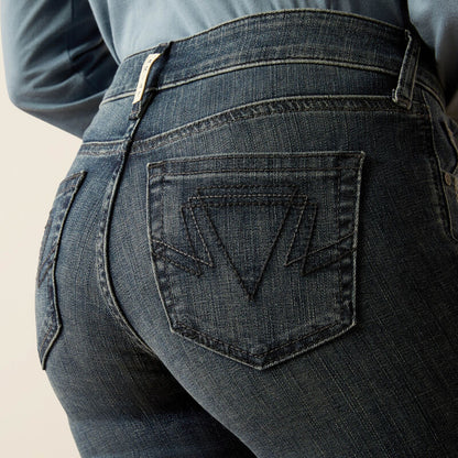 Close-up of dark blue jeans with a brand logo on the back pocket against a neutral background
